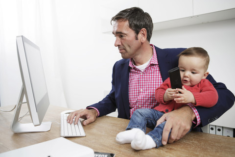 Geschäftsmann mit kleinem Jungen arbeitet von zu Hause aus, lizenzfreies Stockfoto