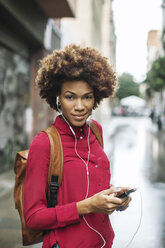 Smiling young woman hearing music with earphones - EBSF000365