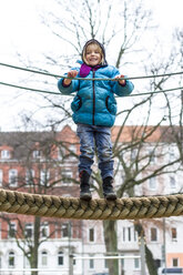Little girl standing on playground equipment - JFEF000536