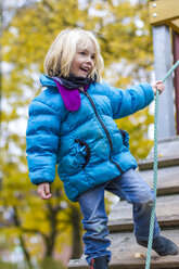 Happy little girl standing on playground equipment - JFEF000538