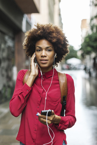 Porträt einer jungen Frau, die mit Kopfhörern Musik hört, lizenzfreies Stockfoto