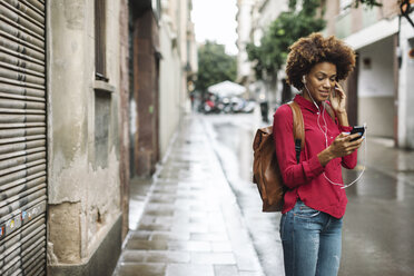 Smiling young woman hearing music with earphones - EBSF000376