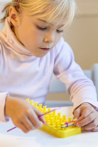 Kleines Mädchen macht Armbänder mit Loomboard, lizenzfreies Stockfoto