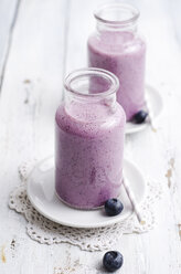 Two glasses of blueberry smoothie on white wood - ODF000871