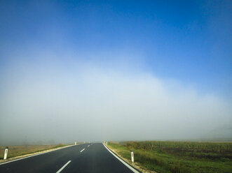 Blauer Himmel und Nebel über leerer Landstraße, Österreich - DISF001093