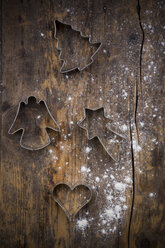 Four different cookie cutters and scattered flour on dark wood - LVF002295