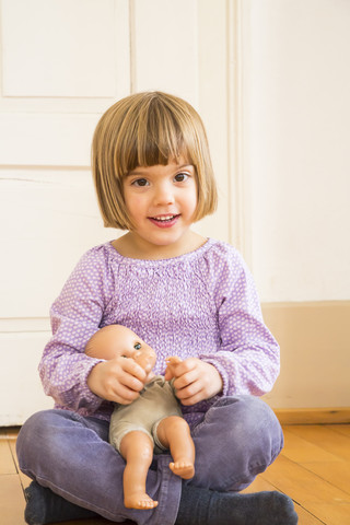 Portrait of smiling little girl playing with doll stock photo