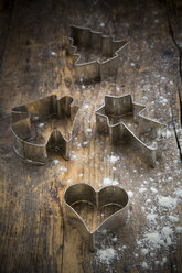 Four different cookie cutters and scattered flour on dark wood - LVF002297