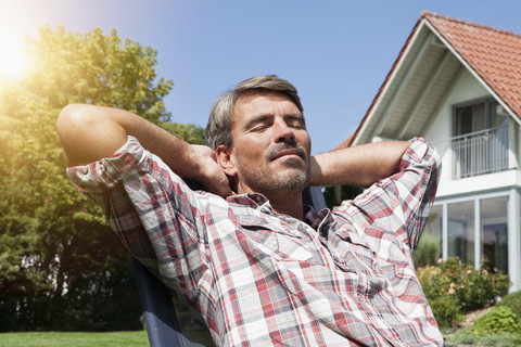 Entspannter Mann im Liegestuhl im Garten, lizenzfreies Stockfoto