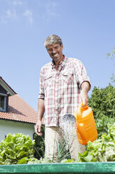 Mann bewässert Pflanzen im Garten - RBF001923