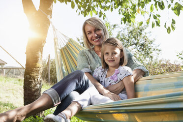 Happy mother and daughter sitting in hammock - RBF001963