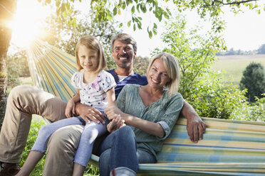 Happy family sitting in hammock - RBF001965