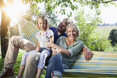 Happy family sitting in hammock - RBF001966