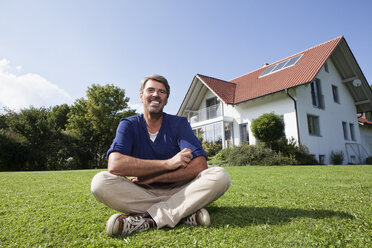 Smiling man sitting on lawn in garden - RBF001973