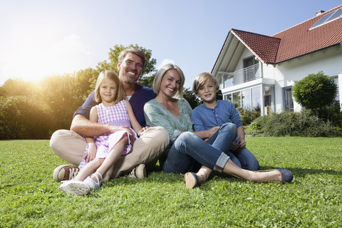 Happy family sitting on lawn in garden stock photo
