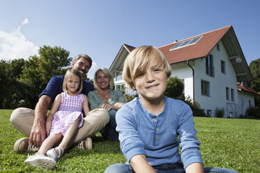 Happy family sitting on lawn in garden - RBF001980