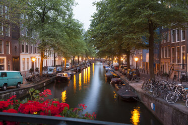 Niederlande, Amsterdam, Blick auf Reihen von alten Wohnhäusern am Stadtkanal in der Abenddämmerung - FCF000473