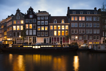 Netherlands, Amsterdam, view to row of lighted old residential houses at town canal by evening twilight - FCF000475