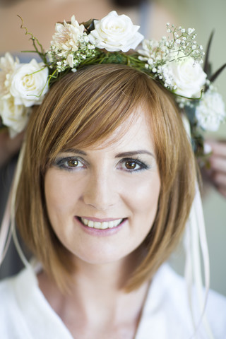 Porträt einer lächelnden jungen Frau mit Blumenkranz im Haar, lizenzfreies Stockfoto