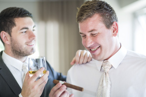 Groom smoking a cigar with best man before wedding stock photo