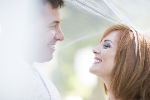 Glücklicher Bräutigam und Braut unter Schleier bereit für ihre Hochzeit, lizenzfreies Stockfoto