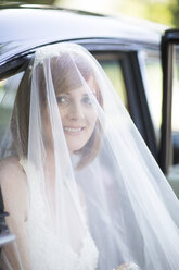 Lächelnde Braut beim Aussteigen aus dem Auto vor ihrer Hochzeit - ZEF002563