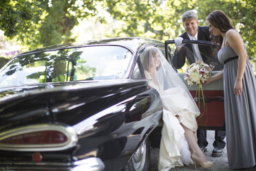 Braut steigt vor ihrer Hochzeit mit Fahrer und Brautjungfer aus dem Auto aus - ZEF002566