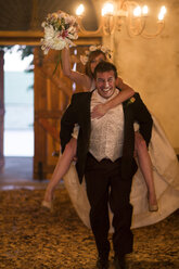 Glücklicher Bräutigam trägt Braut huckepack in der Lobby - ZEF002791