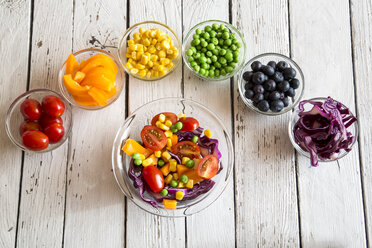 Gemischter Salat und Glasschalen mit verschiedenen Rohkostsorten in Regenbogenfarben auf weißem Holz angeordnet - SARF001055