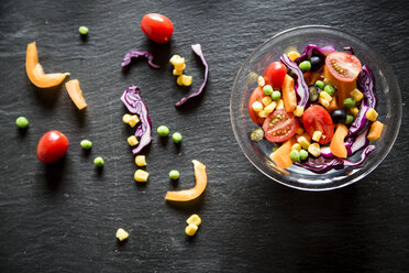 Glass bowl with mixed salad and different raw vegetables on slate - SARF001057