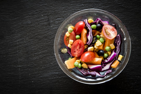 Glasschale mit gemischtem Salat auf Schiefer, lizenzfreies Stockfoto