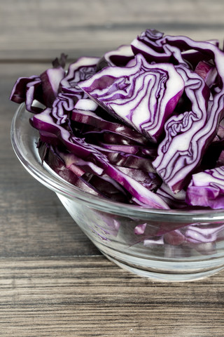 Glasschale mit geschnittenem Rotkohl auf dunklem Holz, lizenzfreies Stockfoto