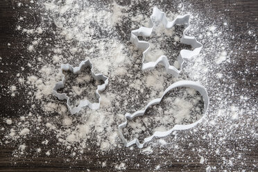 Three cookie cutters on scattered flour and dark wood - SARF001062