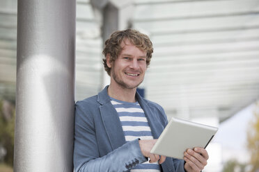 Porträt eines lächelnden Mannes mit digitalem Tablet - RBF002083