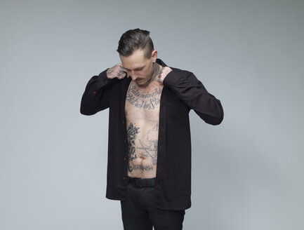 Mann mit Tätowierung auf seiner Taille bis Dressing schwarzes Hemd vor grauem Hintergrund - RH000394