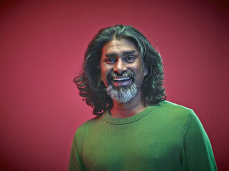 Porträt eines lächelnden Mannes vor einem roten Hintergrund - RH000439