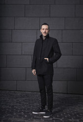 Portrait of black dressed man in front of grey background - RHF000440