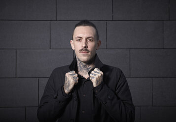 Portrait of serious looking man with tatoos on his hands and his neck - RHF000403