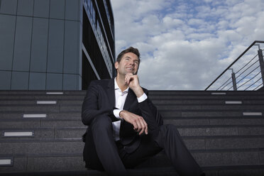 Portrait of smiling businessman sitting on stairs - RHF000442