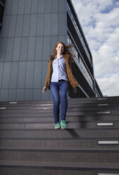 Portrait of smiling young woman walking down the stairs - RHF000413