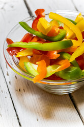 Glass bowl of sliced bell peppers on white wood - SARF001080