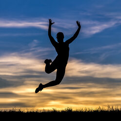 Germany, Silhouette of a woman jumping at sunset - STSF000634