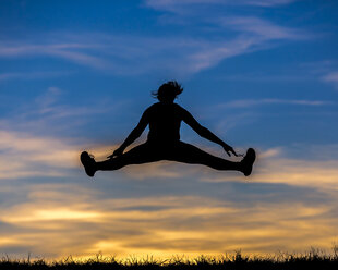 Germany, Silhouette of a woman jumping at sunset - STSF000625