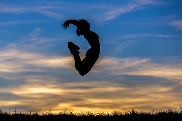 Germany, Silhouette of a woman jumping at sunset - STSF000626