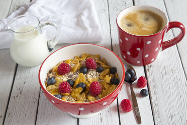 Schale mit Müsli und frischen Früchten, Tasse Kaffee und Milchkännchen auf weißem Holz - SARF001078