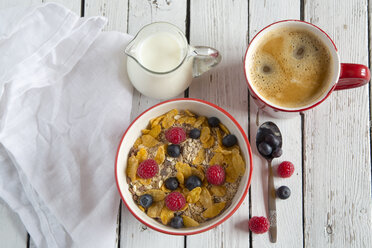 Schale mit Müsli und frischen Früchten, Tasse Kaffee und Milchkännchen auf weißem Holz - SARF001077