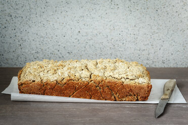 Home-baked buckwheat bread and kitchen knife on paper and wood - EVGF001016