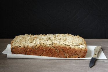 Home-baked buckwheat bread and kitchen knife on paper and wood - EVGF001017