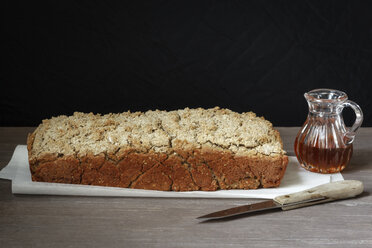 Home-baked buckwheat bread, glass can of honey and kitchen knife on paper and wood - EVGF001018