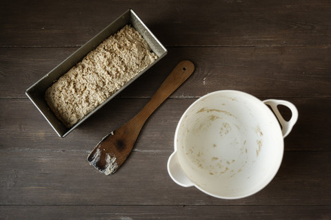 Empty bowl, scraper and baking pan with buckwheat bread dough on wood stock photo